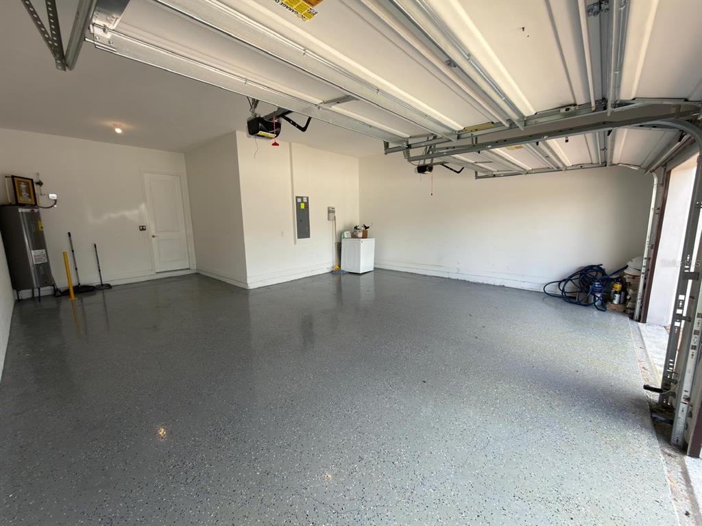 A spacious two-car garage with a gray epoxy floor, white walls, and an open door — 8713 CRESCENDO AVENUE, WINDERMERE, FL