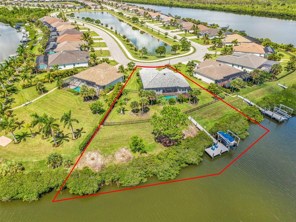 An aerial view shows a waterfront house with a pool, dock, and large fenced yard — 15336 SPANISH POINT DRIVE, PORT CHARLOTTE, FL