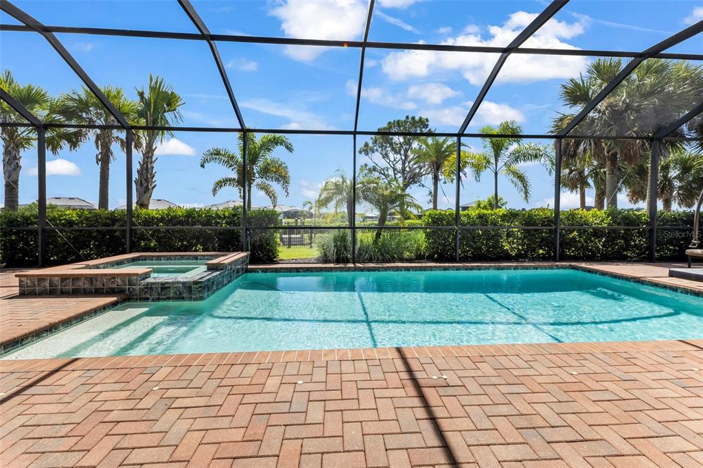 A screened-in patio features a swimming pool, a raised spa, and brick paver decking — 15336 SPANISH POINT DRIVE, PORT CHARLOTTE, FL