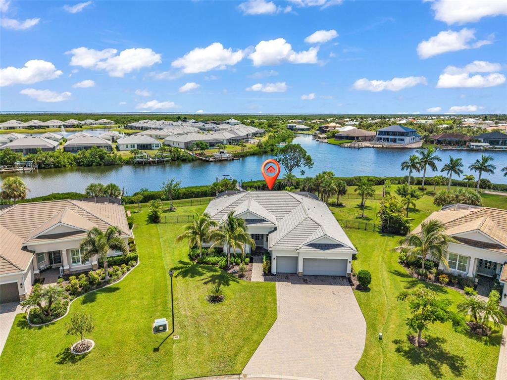 An aerial view shows a single-story house with a tile roof, driveway, and backyard waterfront — 15336 SPANISH POINT DRIVE, PORT CHARLOTTE, FL