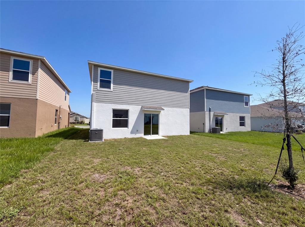 The rear exterior of a two-story house with a white stucco base and gray siding — 2142 LASSO LOOP, EAGLE LAKE, FL