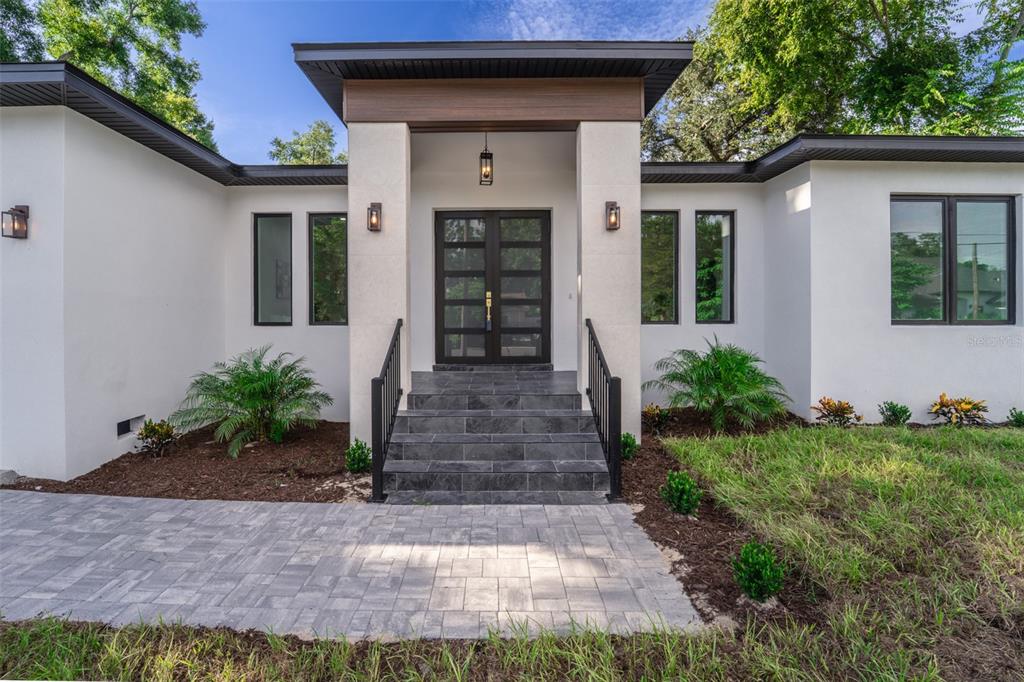 The exterior of a modern white house features a dark tiled staircase and double front doors — 8326 JUNE STREET, TAMPA, FL