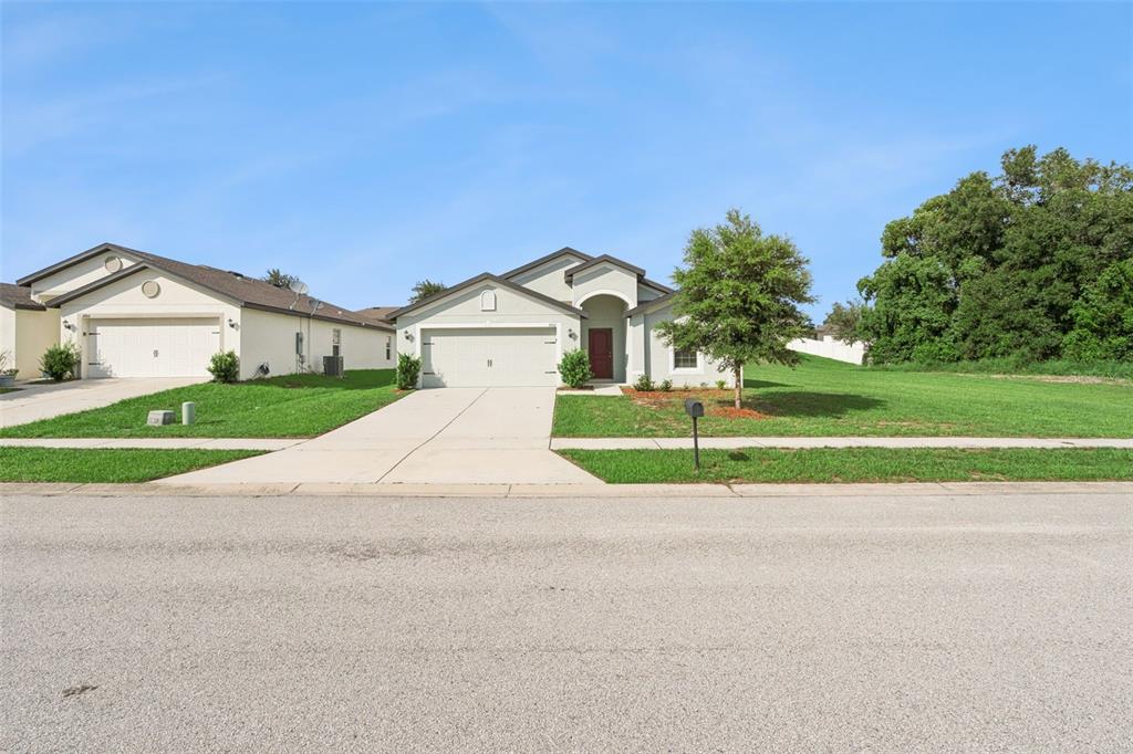 A single-story suburban house with a two-car garage and a large side yard — 1602 ORNE STREET, MASCOTTE, FL