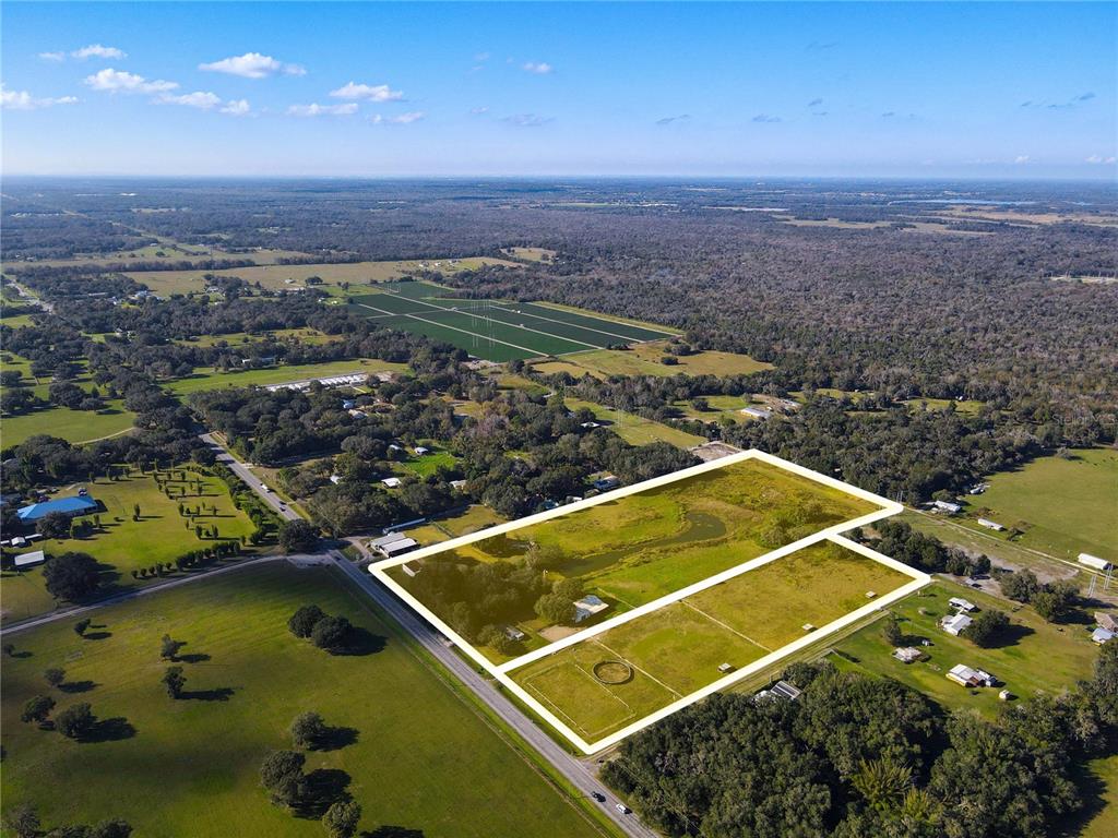 An aerial view shows a large, rectangular plot of land outlined in yellow — 8719 & 8809 LITHIA PINECREST ROAD, LITHIA, FL