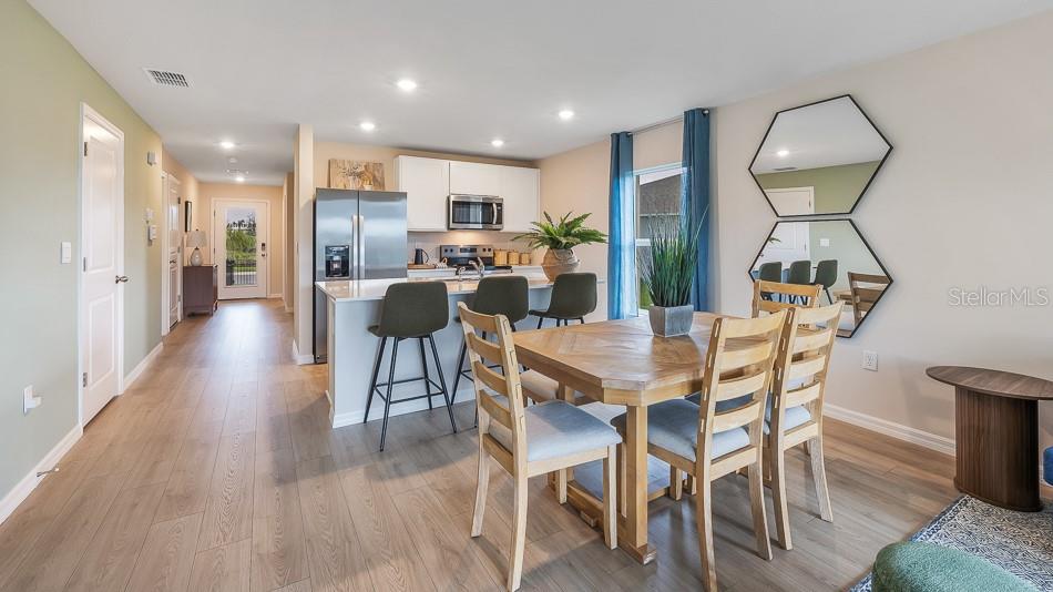 A dining area with a wooden table and chairs sits adjacent to a modern kitchen — 10424 CURVING CREEK LOOP, PARRISH, FL