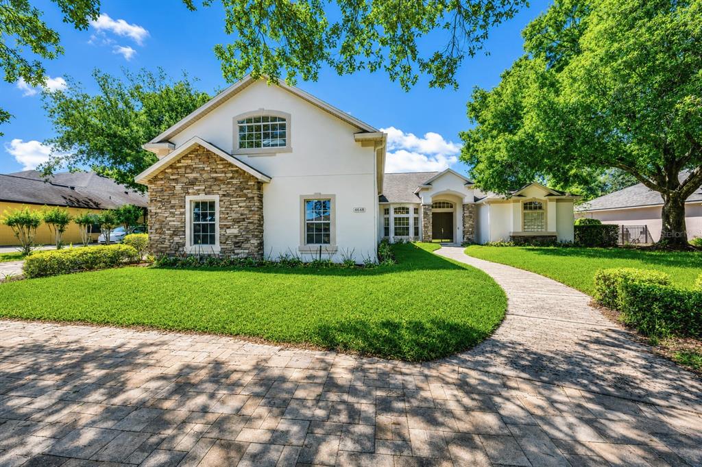 A two-story house with a stone facade, white stucco walls, and a paved walkway — 9548 CROWN PRINCE LANE, WINDERMERE, FL