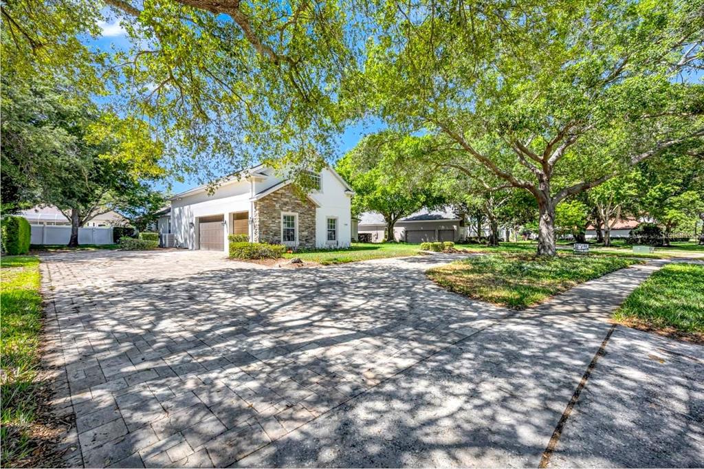A two-story house with a stone facade and a large paved driveway under mature trees — 9548 CROWN PRINCE LANE, WINDERMERE, FL