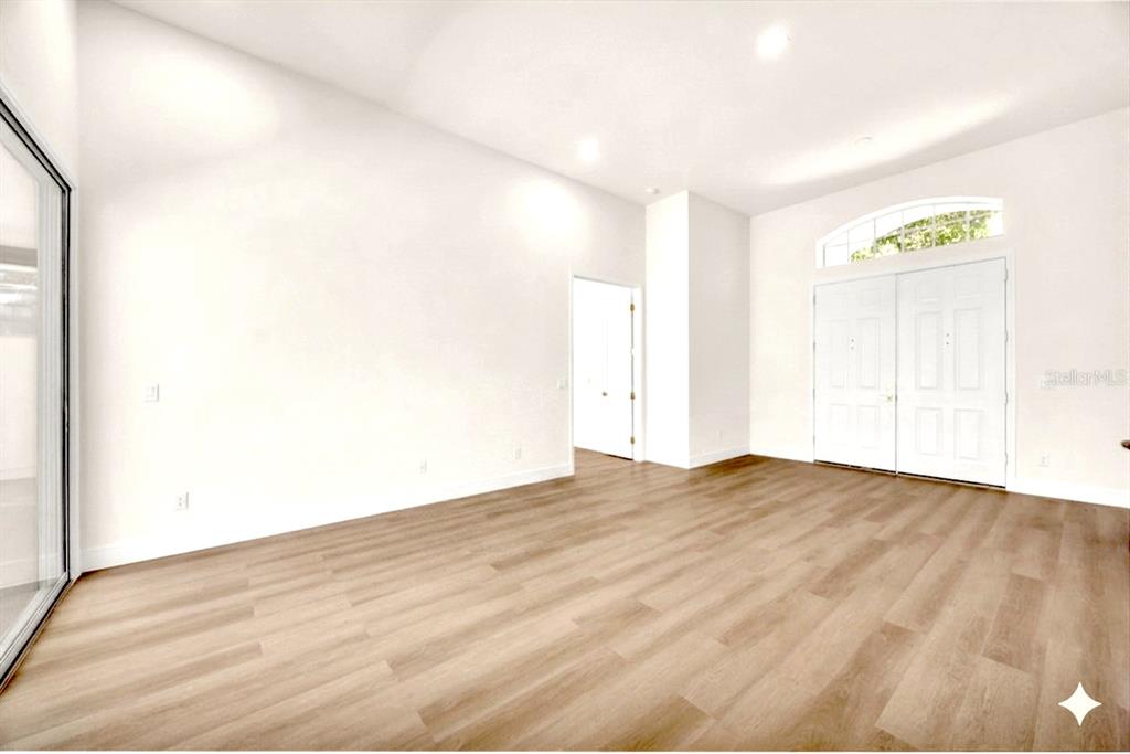 An empty room with light wood-look flooring, white walls, and a double-door entryway — 9548 CROWN PRINCE LANE, WINDERMERE, FL