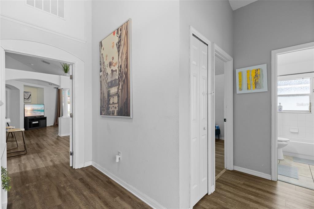 A hallway with wood-look flooring leads to a living area, a closet, and a bathroom — 611 SADDLE RIDGE DRIVE, DAVENPORT, FL