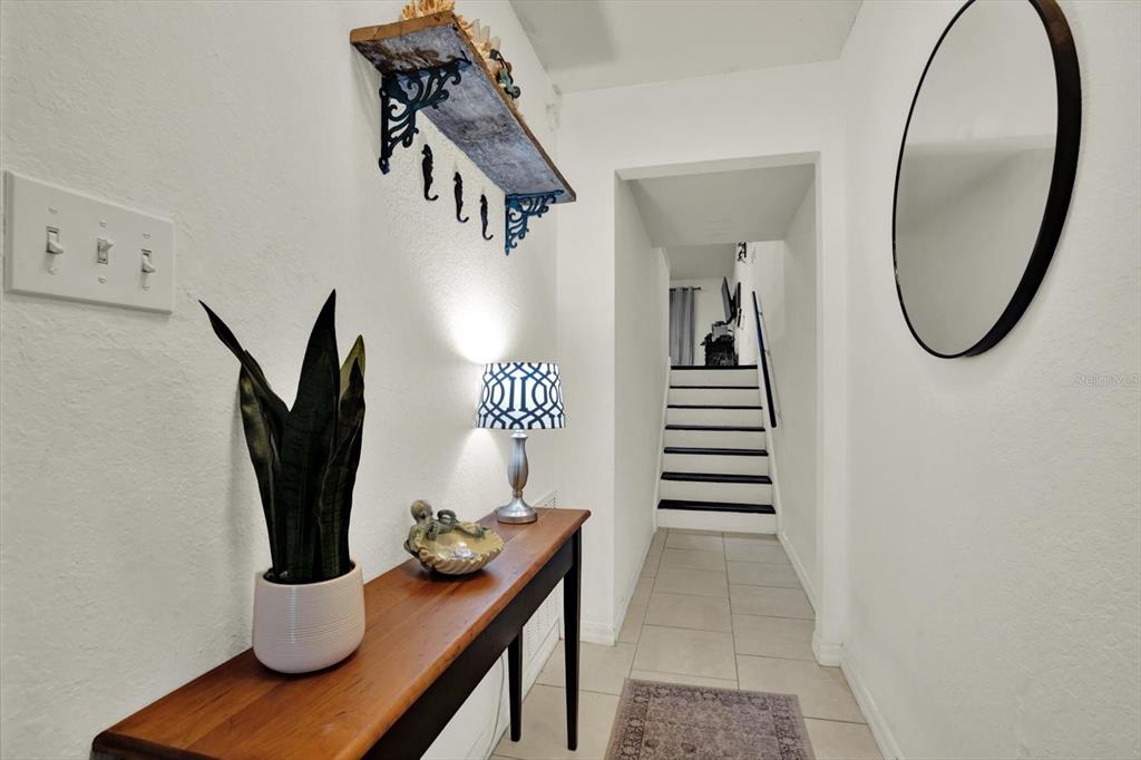 A hallway features a wooden console table, a decorative shelf, and stairs in the background — 6311 93RD TERRACE N UNIT 4403, PINELLAS PARK, FL