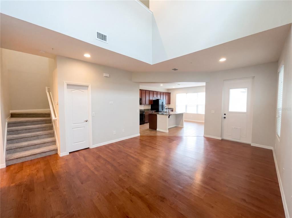 An open-concept living area features hardwood floors, a staircase, and a view into the kitchen — 5545 BOWMAN DRIVE, WINTER GARDEN, FL