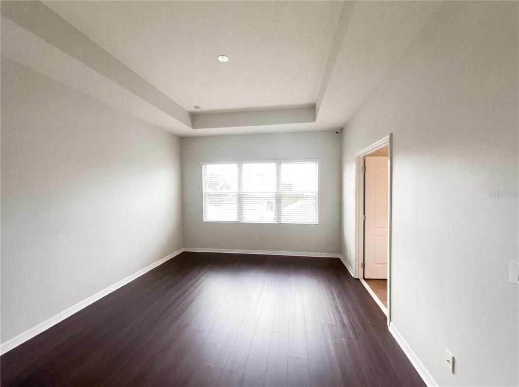 An empty room with dark wood flooring, white walls, and a tray ceiling — 5545 BOWMAN DRIVE, WINTER GARDEN, FL