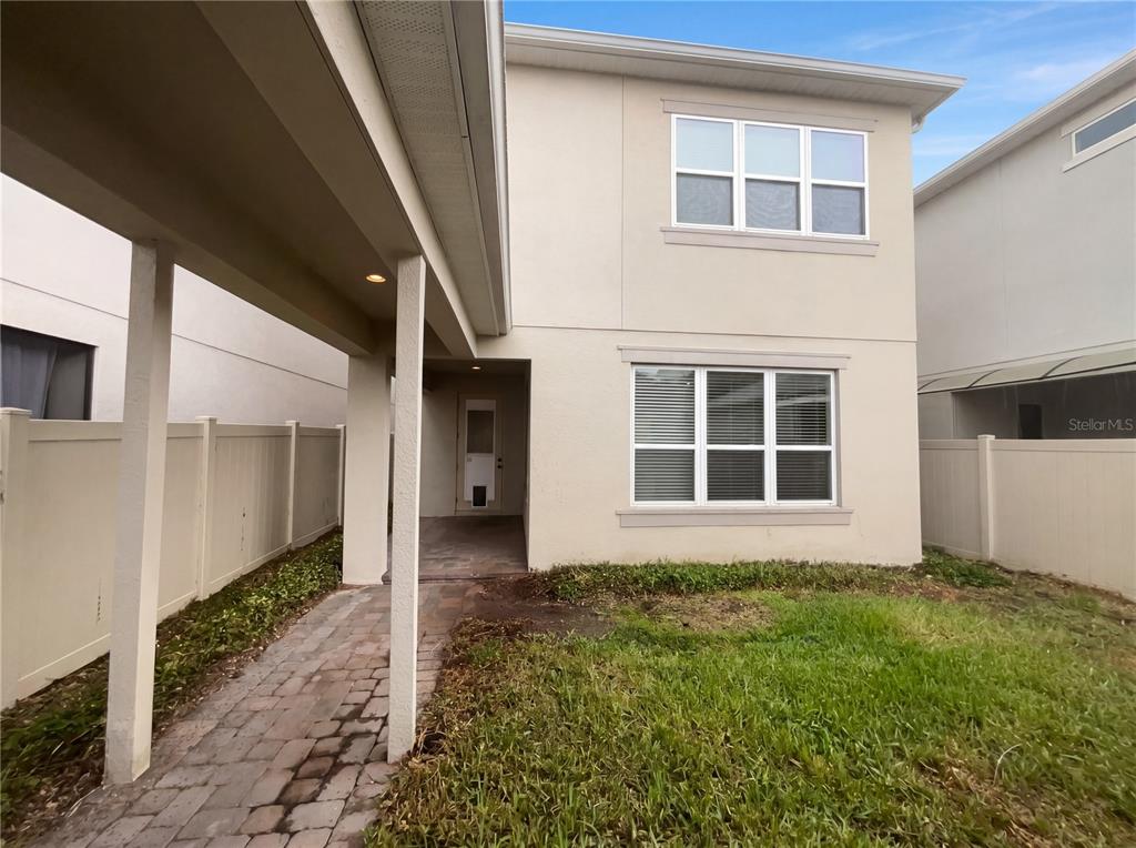 A two-story house exterior features a covered walkway, a paved path, and a small lawn — 5545 BOWMAN DRIVE, WINTER GARDEN, FL