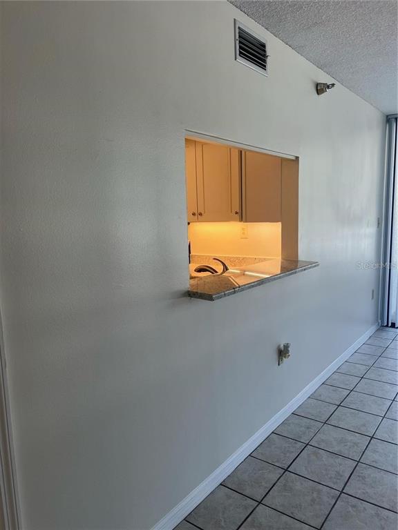 A view of a kitchen pass-through window with a granite countertop and tiled flooring — 690 ISLAND WAY UNIT 208, CLEARWATER, FL