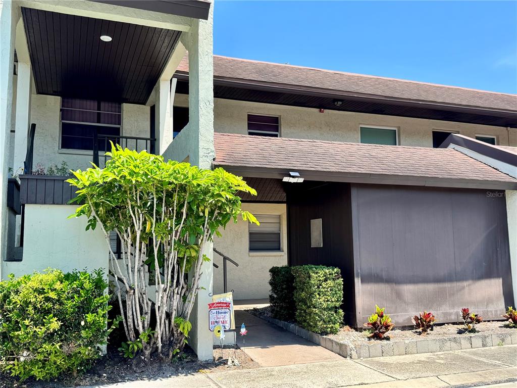 An exterior view of a two-story apartment building with a covered entryway and landscaping — 1100 E BAY DRIVE UNIT 3, LARGO, FL