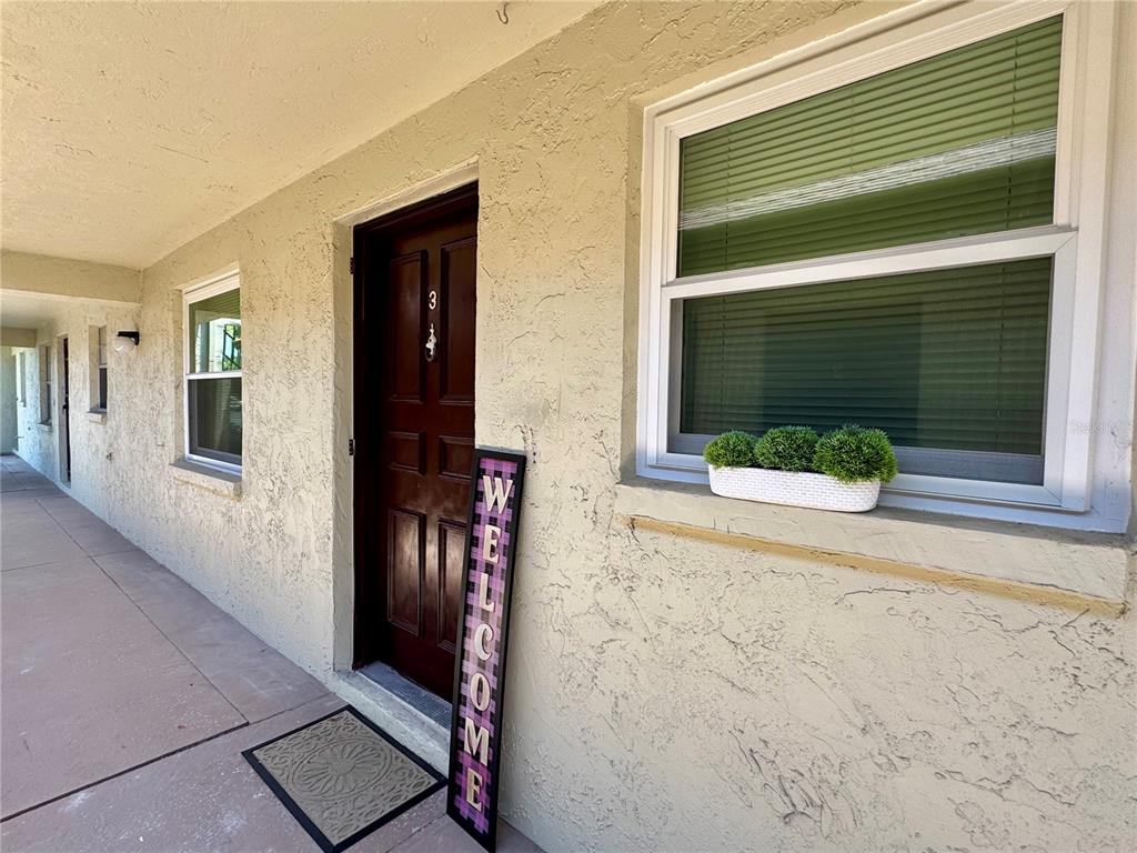 An exterior view of a building entrance with a brown door, window, and welcome sign — 1100 E BAY DRIVE UNIT 3, LARGO, FL