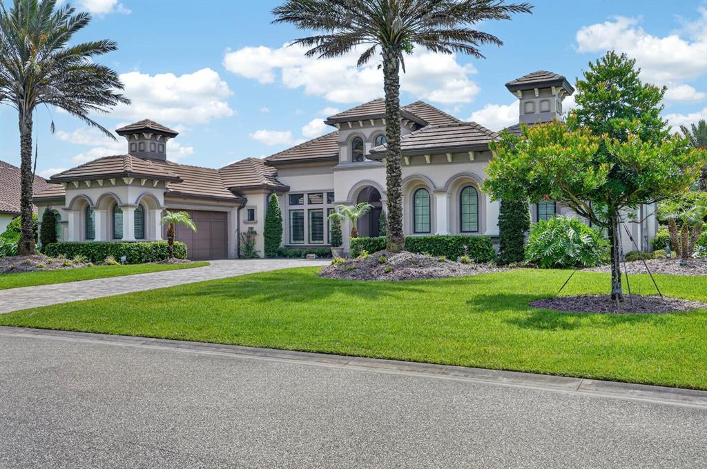 A large, single-story Mediterranean-style house with a tile roof, arched windows, and palm trees — 1023 SUDBURY LANE, ORMOND BEACH, FL