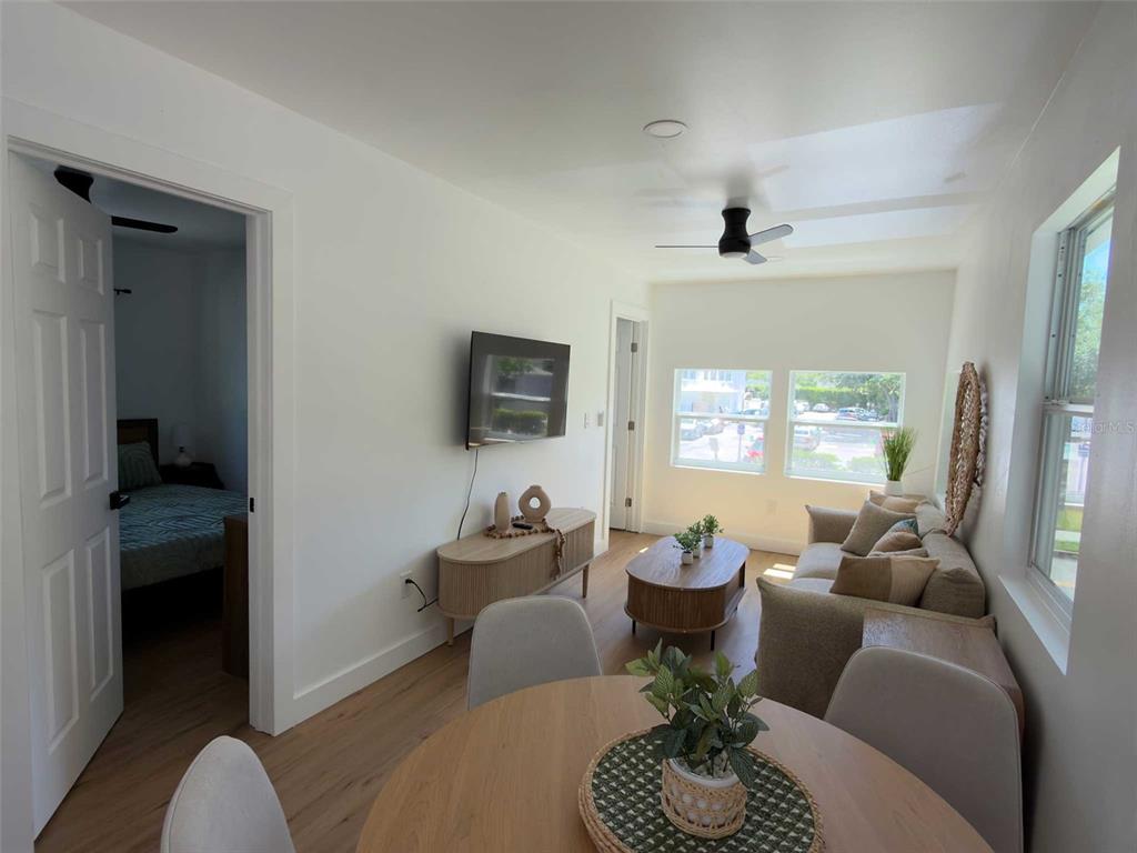 A living room with light wood floors, a dining table, and a sofa near windows — 612 N HAMPTON AVENUE, ORLANDO, FL