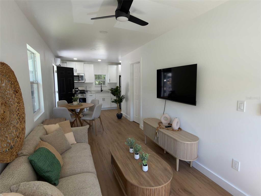 A living room with a sofa, TV, and coffee table opens into a kitchen with dining — 612 N HAMPTON AVENUE, ORLANDO, FL