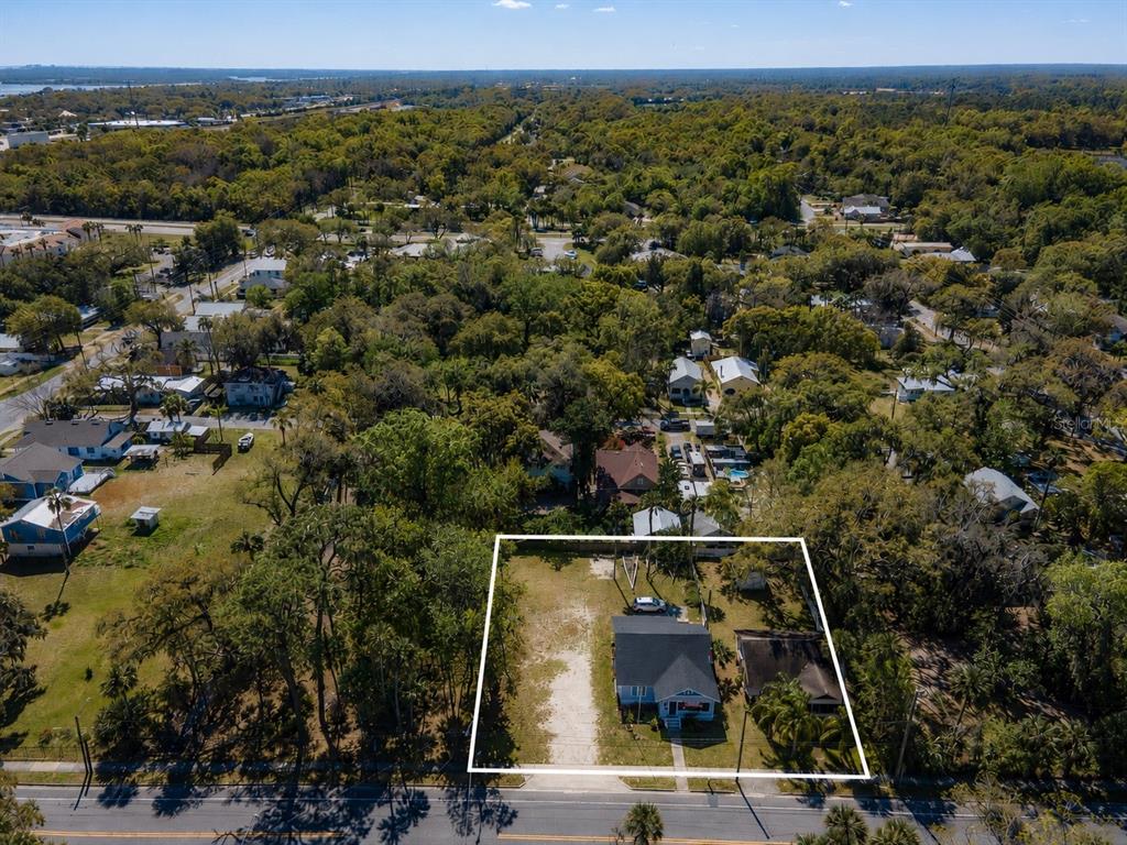 An aerial view shows a house and a detached structure on a large, wooded lot — 820 CANAL STREET, NEW SMYRNA BEACH, FL