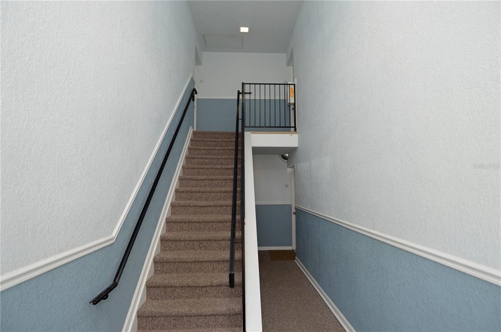 A carpeted staircase with a black metal railing leads to an upper landing — 5245 COQUINA KEY DRIVE SE UNIT D, ST PETERSBURG, FL