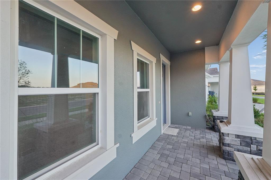 The exterior of a house features a covered porch, stone-based columns, and a gray door — 1953 ARCHING BRANCH DRIVE, ZEPHYRHILLS, FL