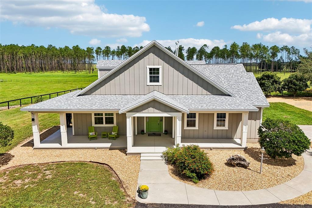 An exterior view of a gray, single-story farmhouse with a covered porch and green door — 2088 NW 102ND BOULEVARD, WILDWOOD, FL