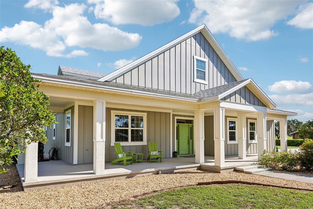 A single-story house with gray vertical siding, a covered front porch, and a lime green door — 2088 NW 102ND BOULEVARD, WILDWOOD, FL