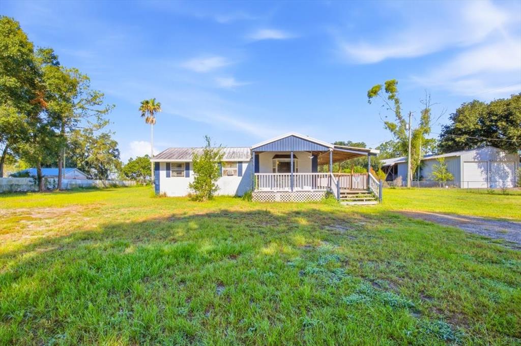 A single-story house with a blue porch and metal roof sits on a grassy lot — 6709 FIVE ACRE RD, PLANT CITY, FL