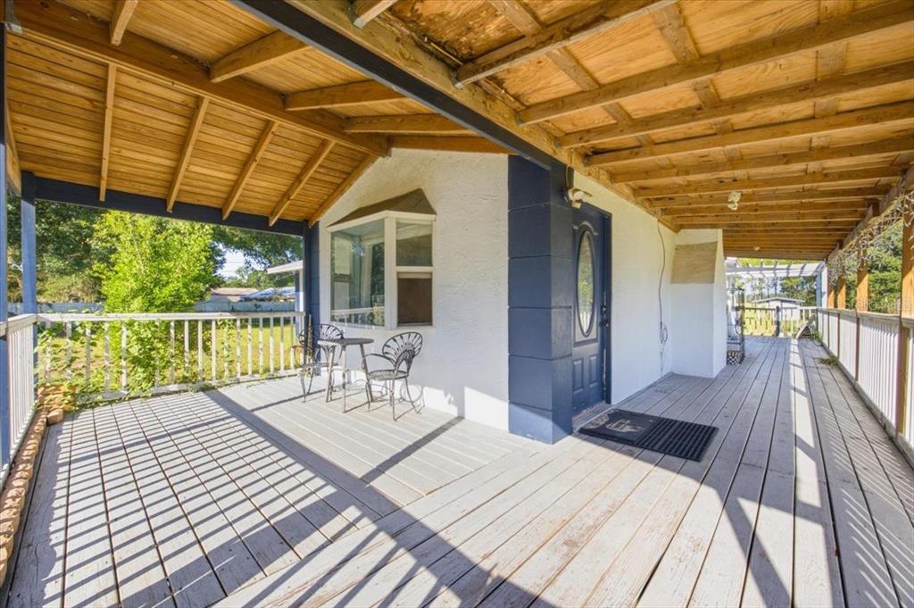 A covered wooden deck features a white exterior wall, a blue door, and patio furniture — 6709 FIVE ACRE RD, PLANT CITY, FL