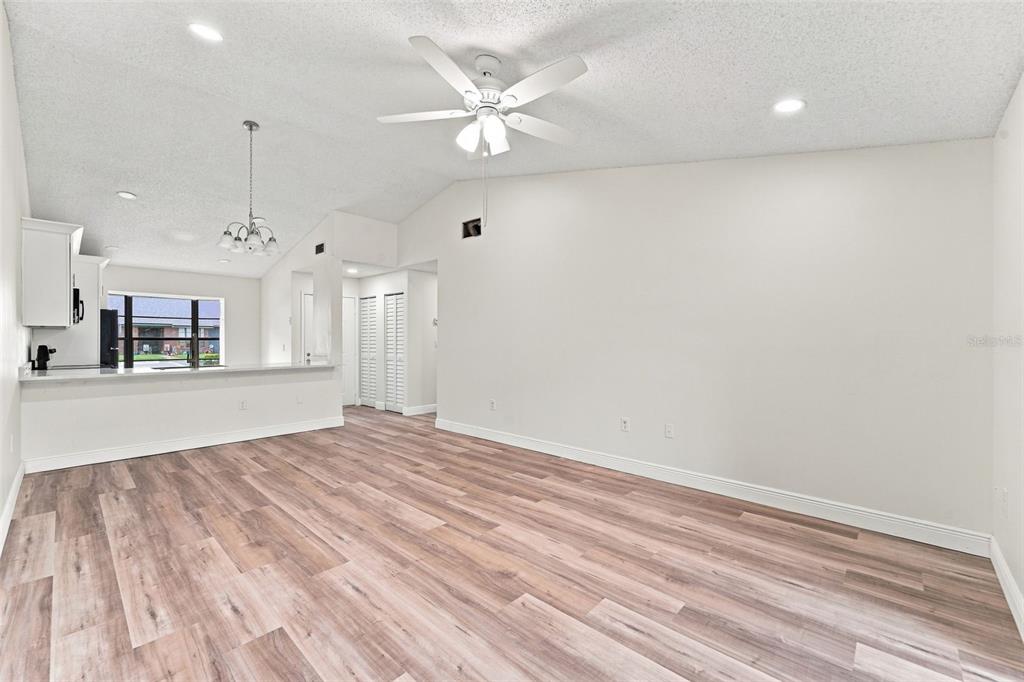 A living room with light wood-look flooring, a vaulted ceiling, and a ceiling fan — 2781 KING OAK CIRCLE, ST CLOUD, FL