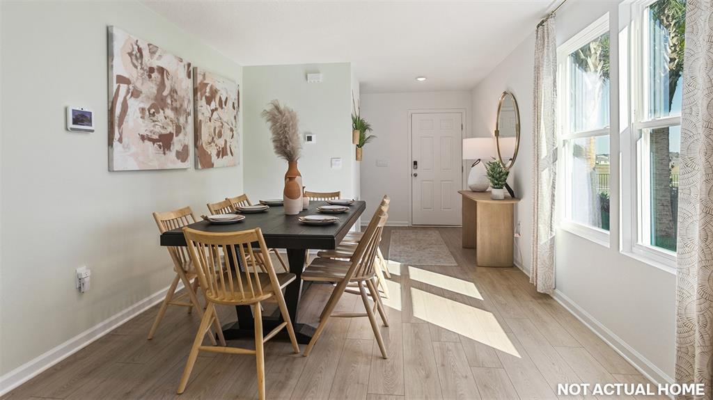 This dining room features a dark wooden table, light wood flooring, and large windows — 73 FLAGSTICK LANE, BUNNELL, FL