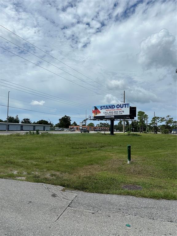 A billboard stands in a grassy lot near a road under a cloudy sky — 4741 PLACIDA ROAD, ENGLEWOOD, FL