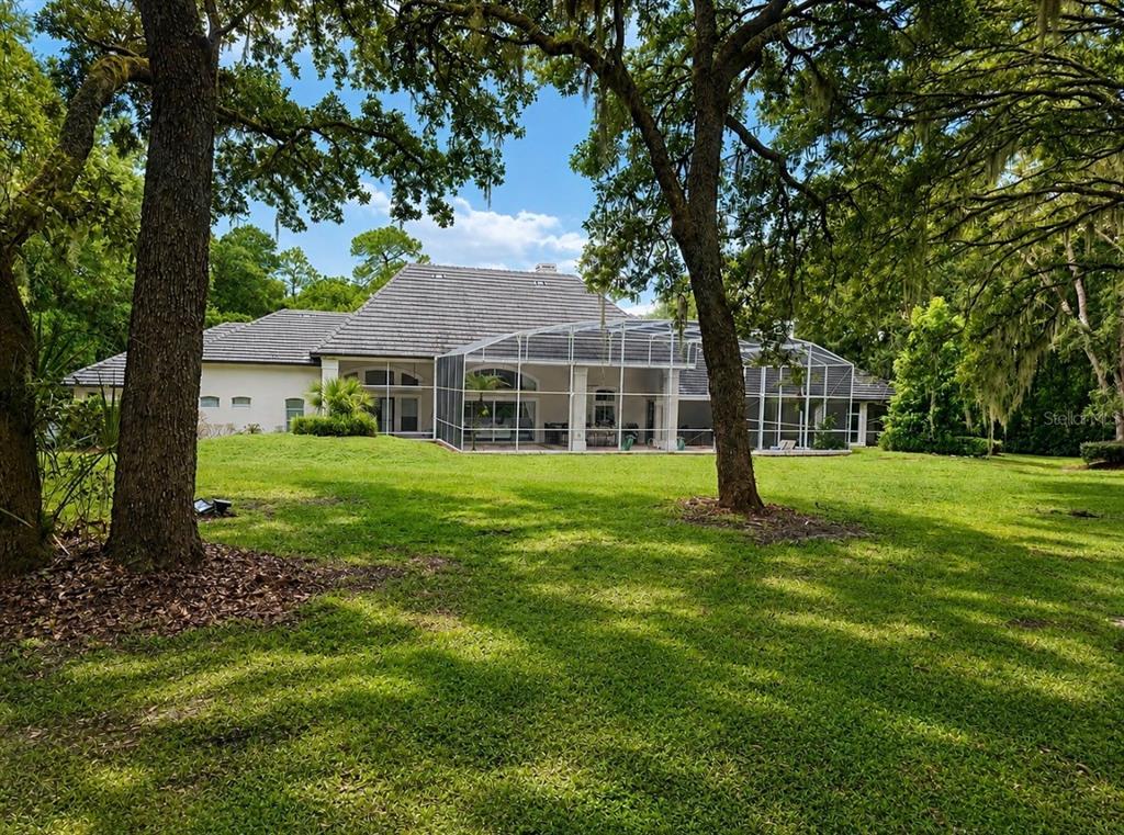 A large, single-story house with a tiled roof and a paved driveway sits on a lawn — 950 SWEETWATER CLUB BOULEVARD, LONGWOOD, FL