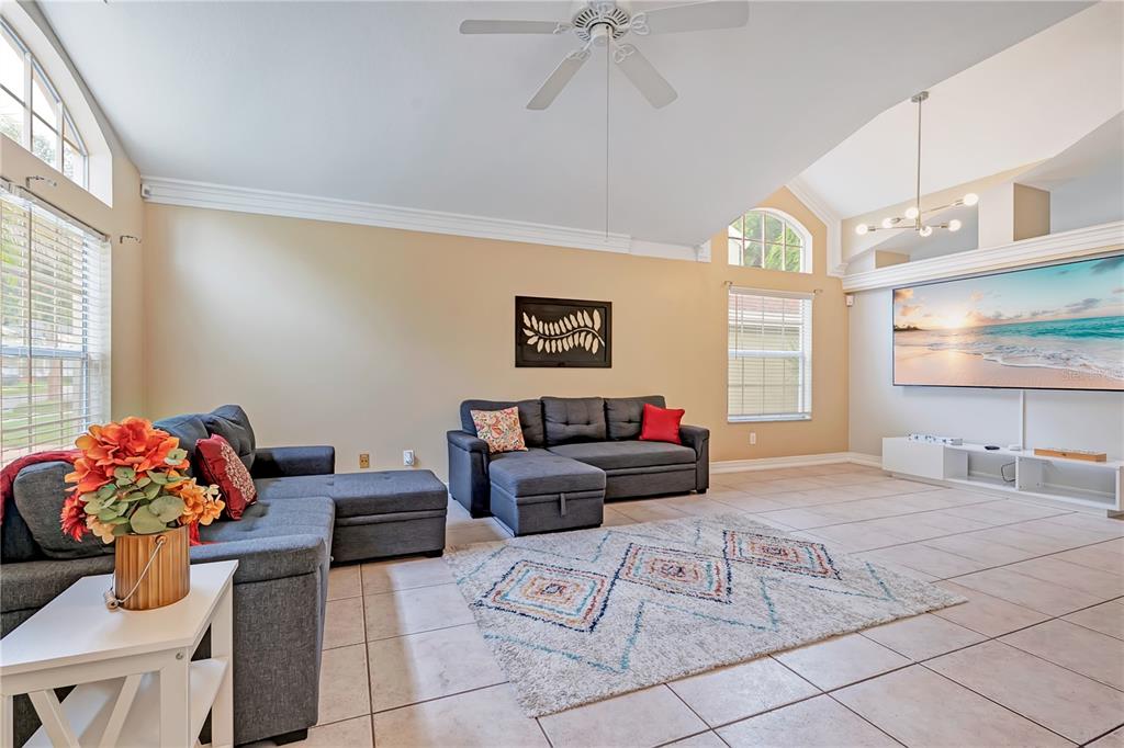 A living room features two gray sectional sofas, a patterned rug, and a large wall-mounted television — 3101 CAYMAN WAY, ORLANDO, FL