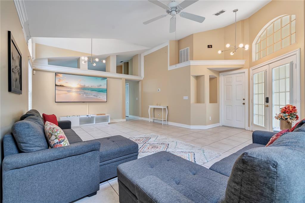 A spacious living room features tile flooring, a vaulted ceiling, and two gray sectional sofas — 3101 CAYMAN WAY, ORLANDO, FL
