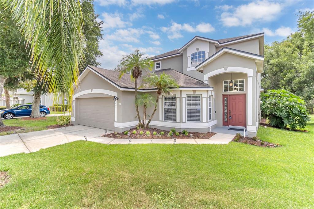 A two-story suburban house with a tan exterior, a two-car garage, and a red front door — 949 PICKFAIR TERRACE, LAKE MARY, FL
