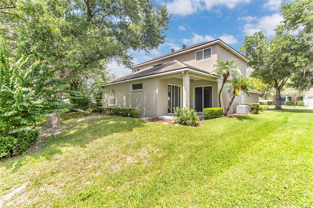 The exterior of a two-story house features a covered patio, lawn, and surrounding trees — 949 PICKFAIR TERRACE, LAKE MARY, FL