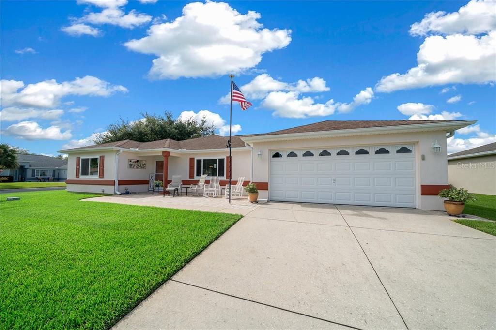 A single-story house with a white garage, a paved patio, and an American flag — 11675 SW 140TH LOOP, DUNNELLON, FL