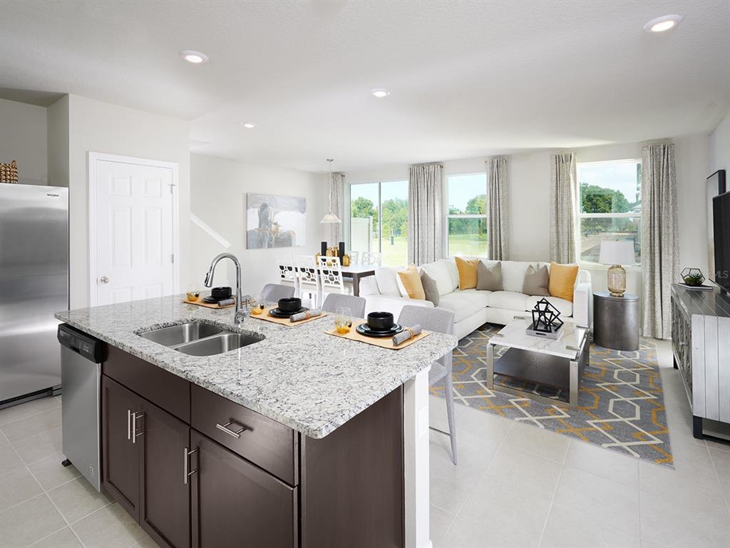 A kitchen island with granite countertops overlooks an open-concept living and dining area — 4559 RANGELAND WAY, ST CLOUD, FL