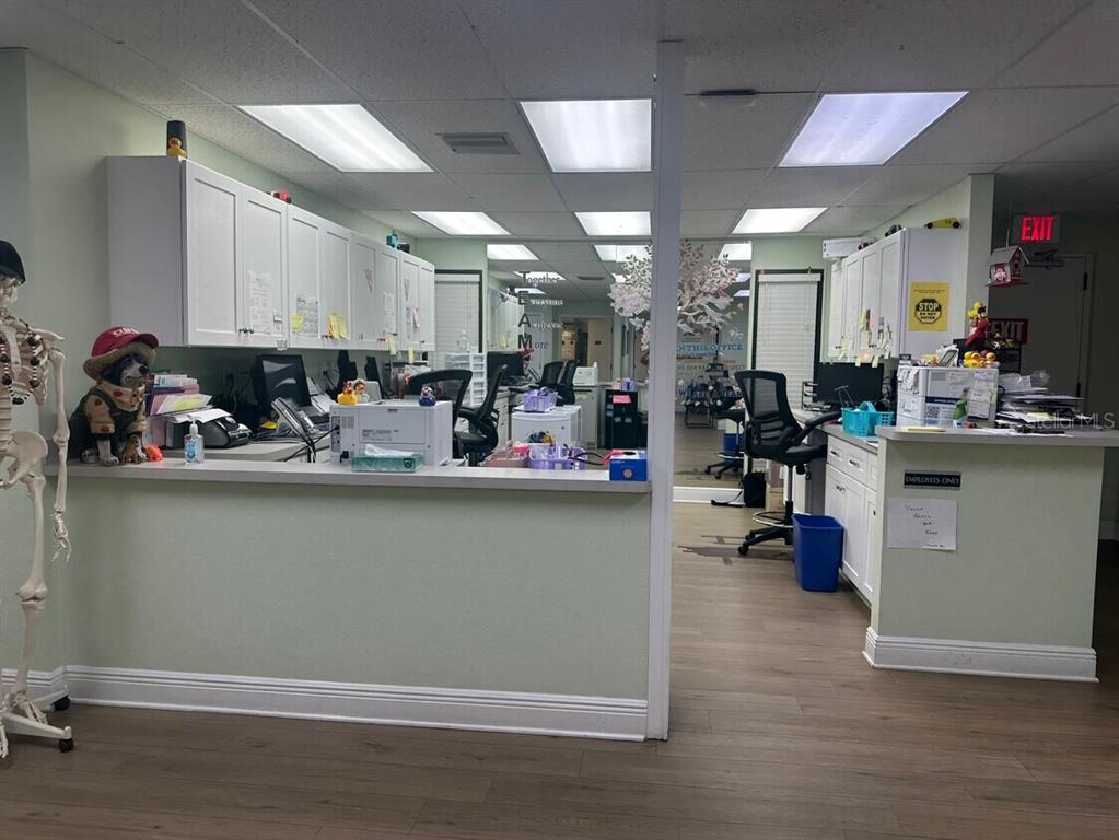 A reception area features a service counter, white cabinetry, office chairs, and a skeleton model — 506 4TH AVENUE W, PALMETTO, FL