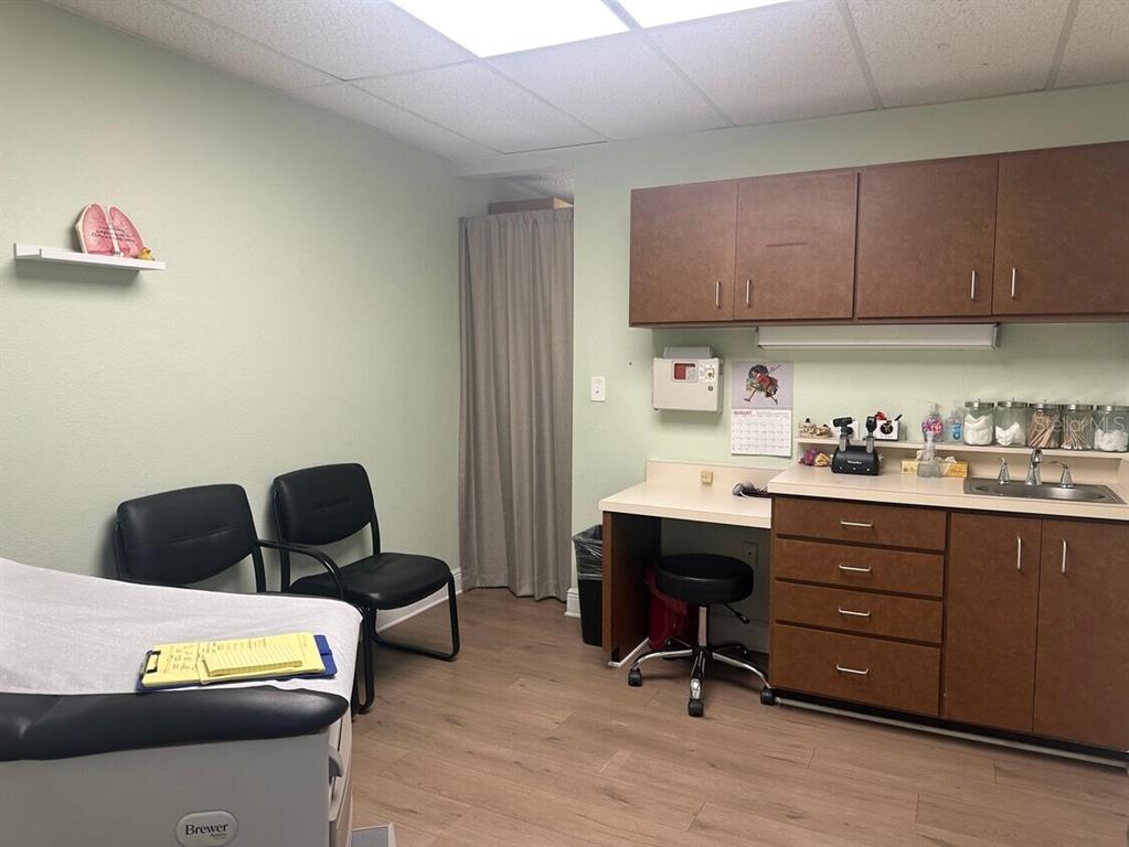 A medical examination room features a treatment table, two chairs, cabinetry, and a sink — 506 4TH AVENUE W, PALMETTO, FL
