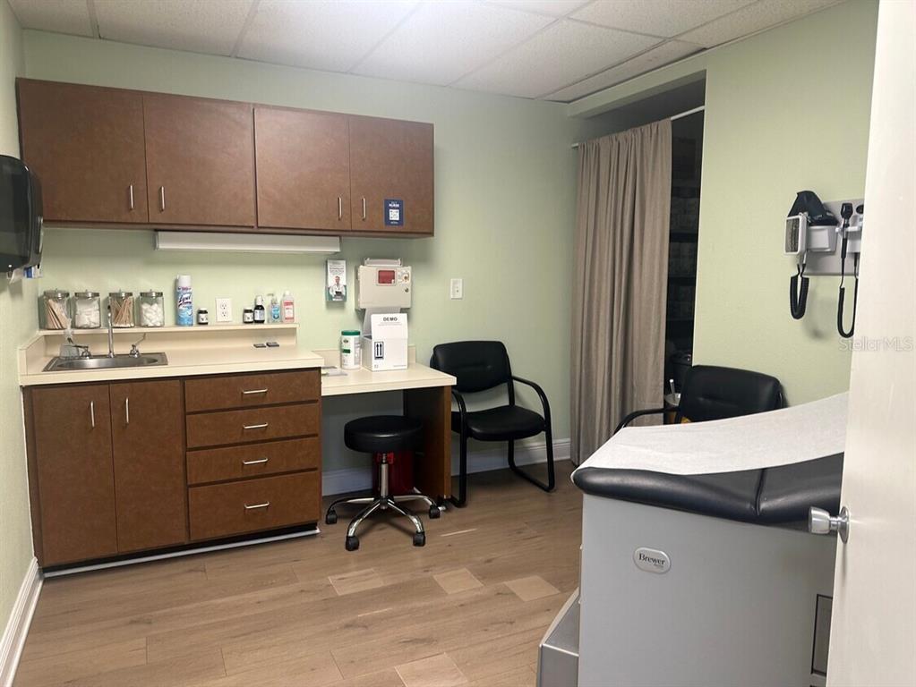 A medical examination room features cabinetry, a sink, a rolling stool, and an exam table — 506 4TH AVENUE W, PALMETTO, FL