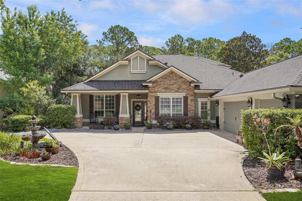 A single-story house with a stone facade, a concrete driveway, and a front yard fountain — 198 PARKSIDE DRIVE, ST AUGUSTINE, FL