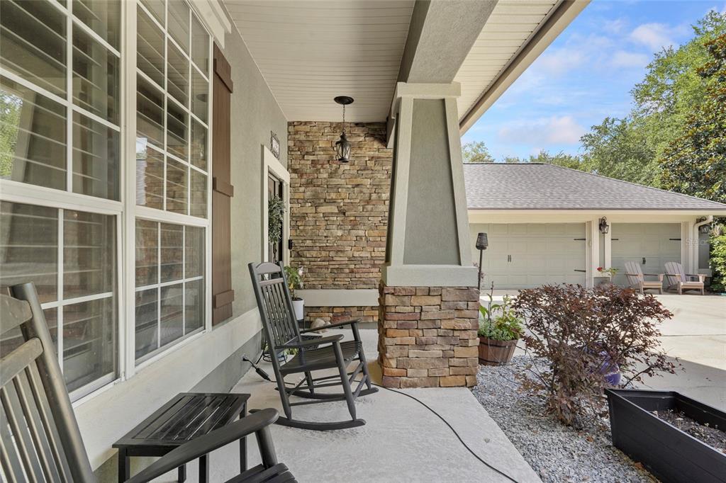 A covered front porch features a stone accent wall, a rocking chair, and a concrete floor — 198 PARKSIDE DRIVE, ST AUGUSTINE, FL