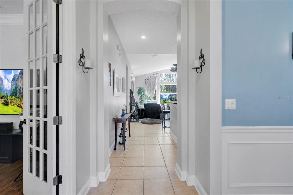 A tiled hallway leads through an arched doorway into a living area with large windows — 198 PARKSIDE DRIVE, ST AUGUSTINE, FL