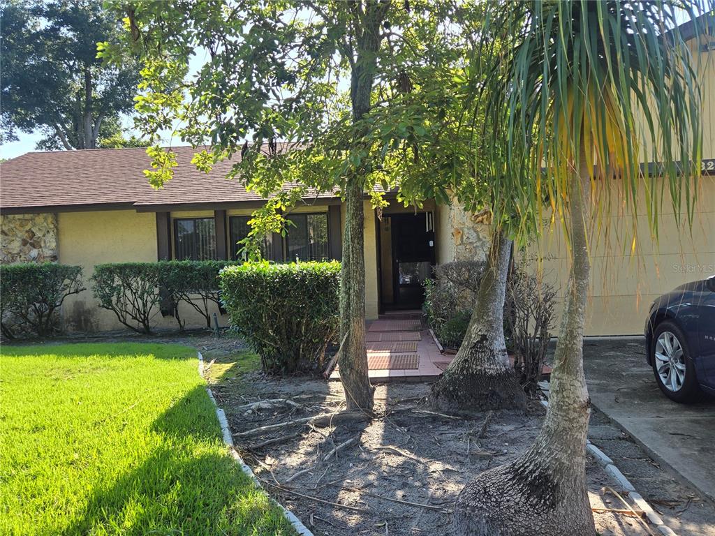 A single-story house with a yellow stucco exterior, stone accents, and a front walkway — 827 RILL DRIVE, ALTAMONTE SPRINGS, FL