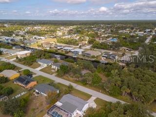 An aerial view shows a residential neighborhood with houses, a canal, and surrounding trees — 18262 VAN NUYS CIRCLE, PORT CHARLOTTE, FL
