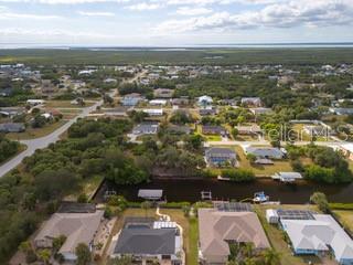 An aerial view shows a residential neighborhood with houses, a canal, and distant water — 18262 VAN NUYS CIRCLE, PORT CHARLOTTE, FL
