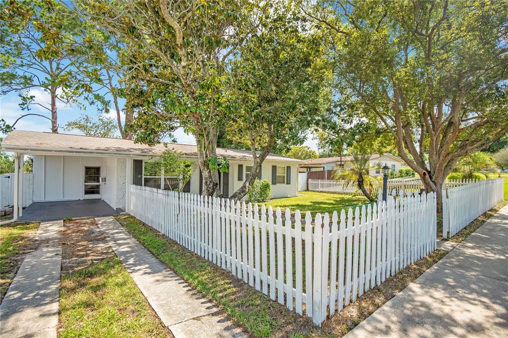 A single-story house with a white picket fence and a storage container in the yard — 682 MERRIMAC STREET, DELTONA, FL